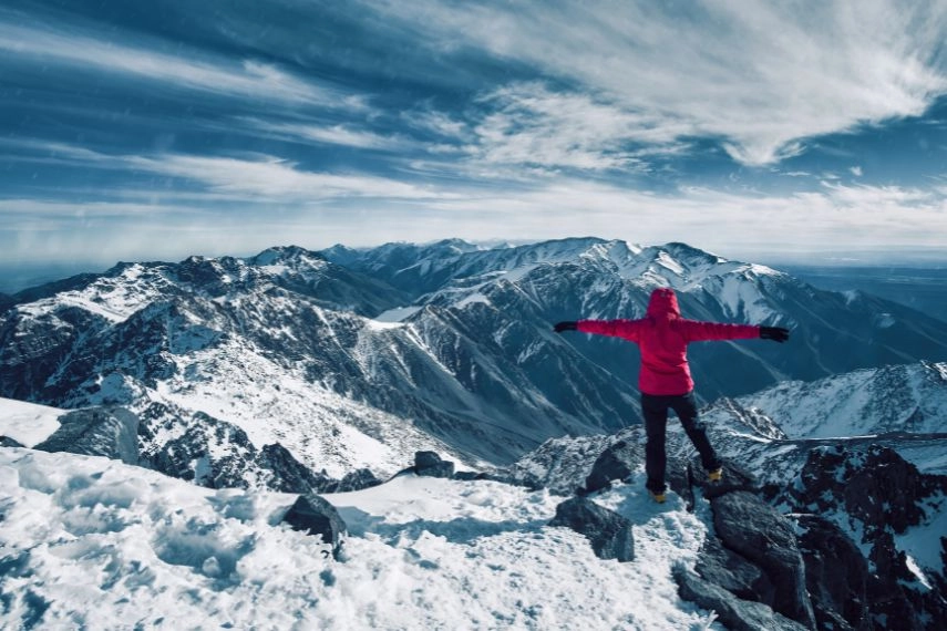 girl standing at snow covered top of the peak of Jebel Toubkal in Atlas mountains Morocco
