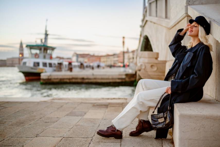 happy smiling woman wearing trendy navy blue trench coat posing in Venice, Italy