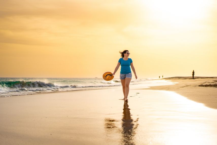 Beautiful woman walking on sunny beach Santa Maria, Sal Island, Cape Verde