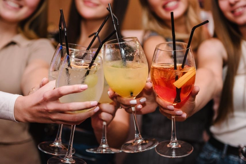Happy young people cheering drinks at bar restaurant in Cancun