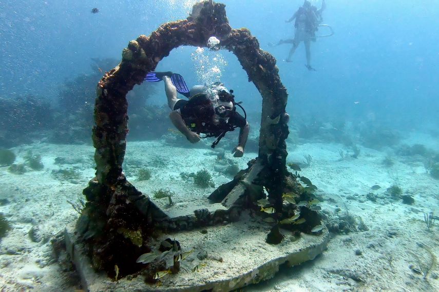 Man scuba diving through hoop at MUSA dive site in cancun mexico