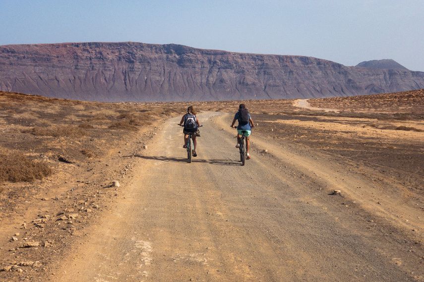 People cycling on a dirt road on the island of La Graciosa