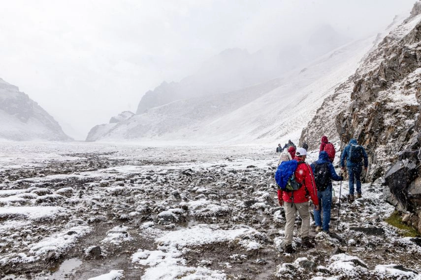 group of tourists with backpacks are marching along a snowy mountain trail in kazakhstan