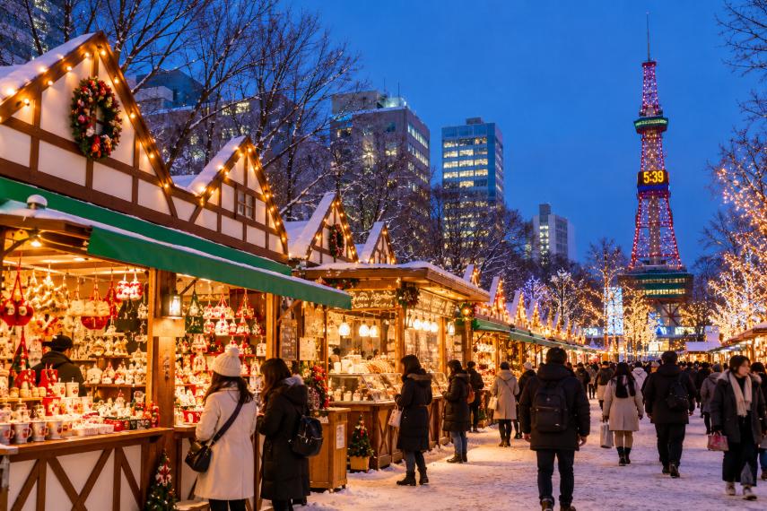 Snowy Christmas market with glowing lights and a tower.